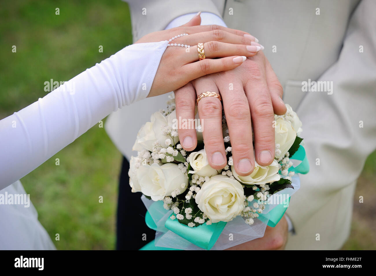 Mano la sposa e lo sposo con gli anelli sul mazzo di nozze Foto Stock