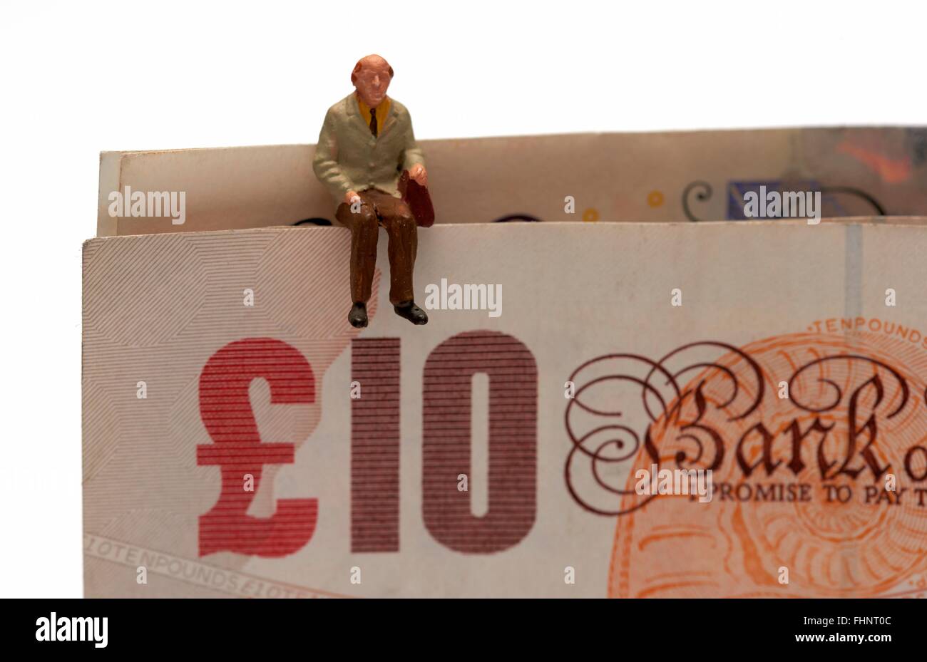 Un maschio in miniatura anziani seduti sulla sommità del British dieci e venti pound note Foto Stock