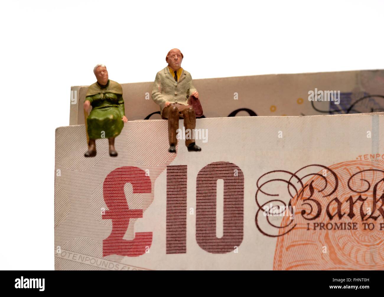 Miniatura due anziani seduti sulla sommità del British dieci e venti pound note Foto Stock