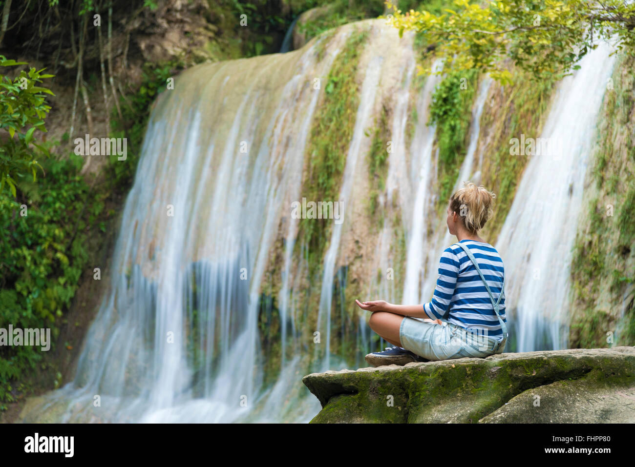 Attraente youn donna durante la meditazione vicino alla cascata, Java, Indonesia Foto Stock