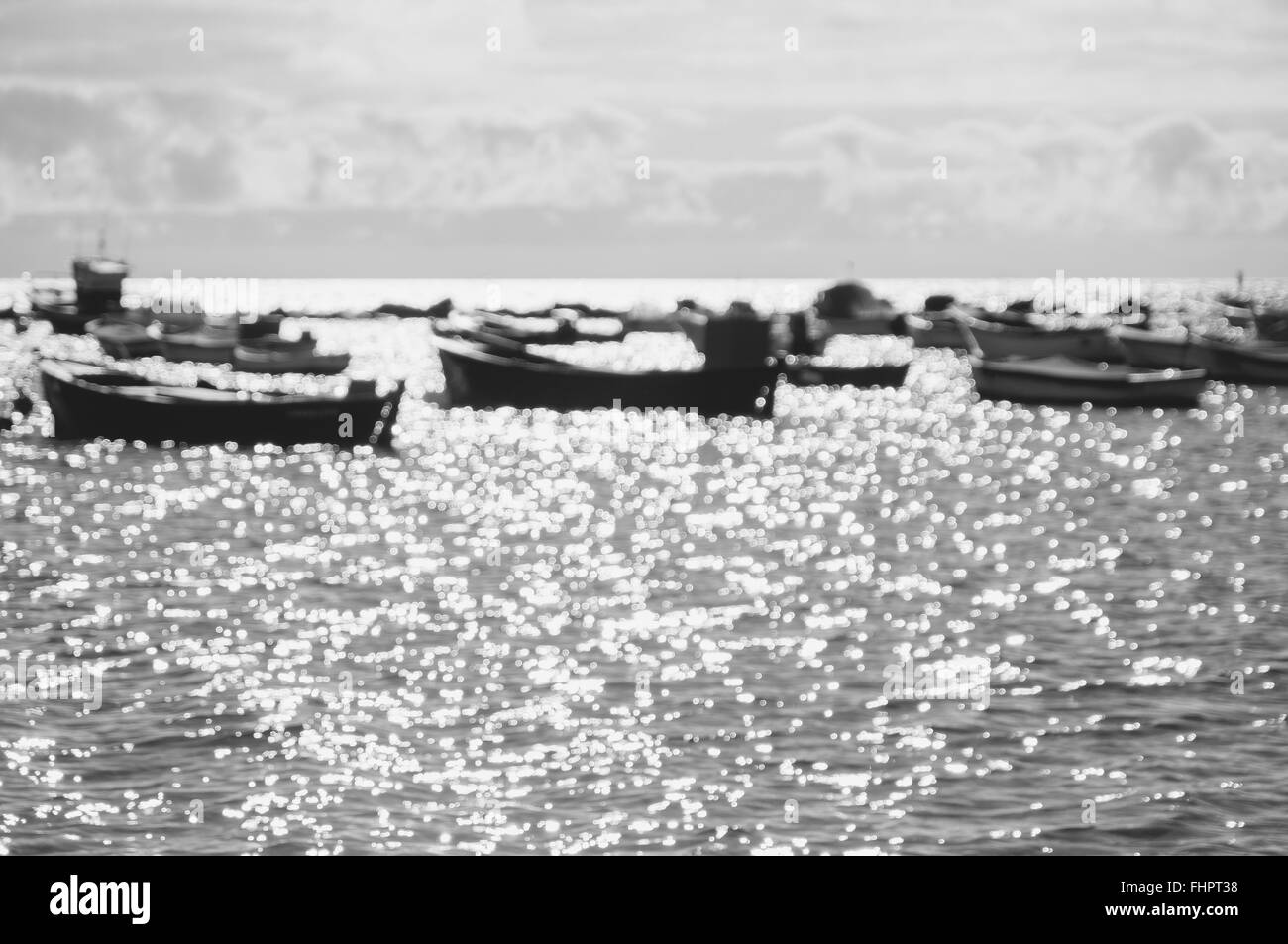 Sfocare lo sfondo di barche contro la luce solare e brilla sulla superficie dell'acqua, immagine in bianco e nero Foto Stock