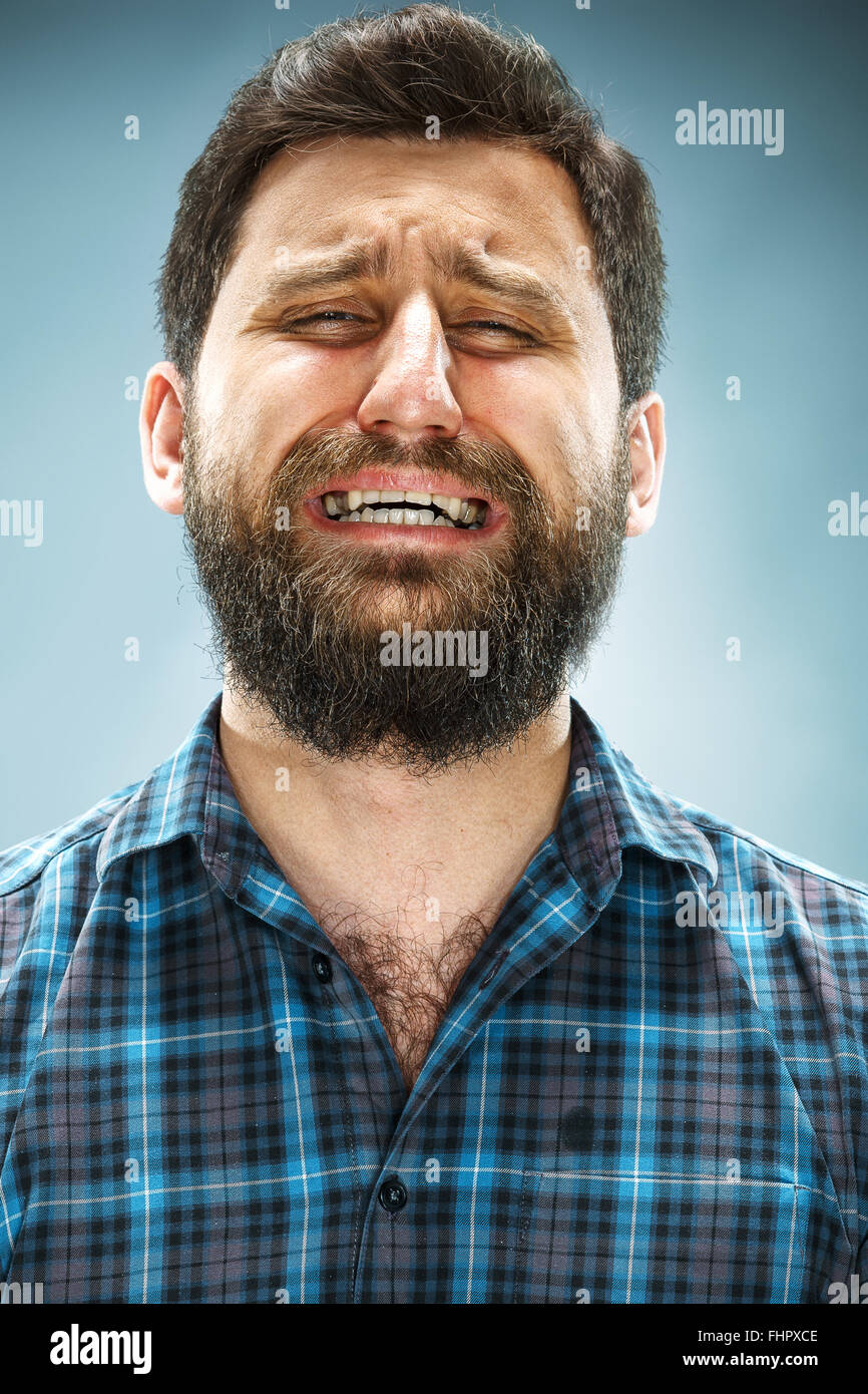 Il pianto uomo sulla faccia closeup su sfondo blu Foto Stock