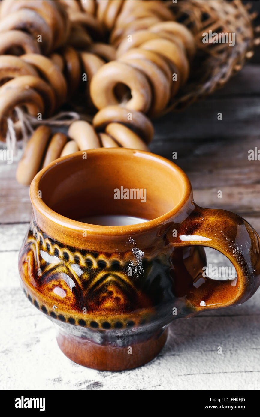 Bagel e bicchiere di latte su sfondo cosparso di farina in stile slavo Foto Stock