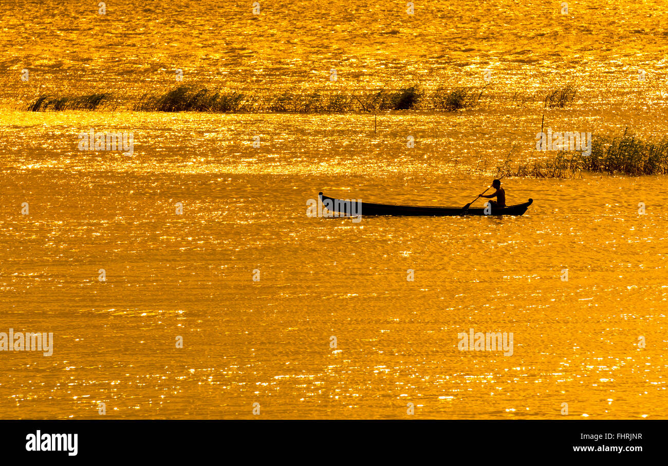 L'uomo paddling barca sul Fiume Ayeyarwady o Irrawaddy, atmosfera serale luce dorata, Mandalay Mandalay Division, Myanmar Foto Stock