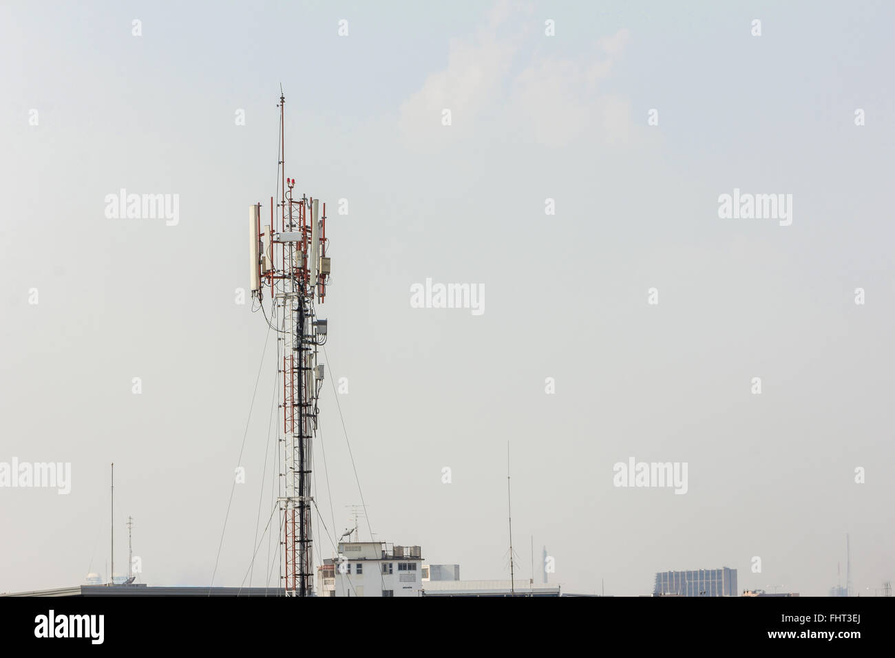 Torre di telecomunicazione con più antenne e trasmettitori di dati con la bella città in background e ampia montagna sono Foto Stock