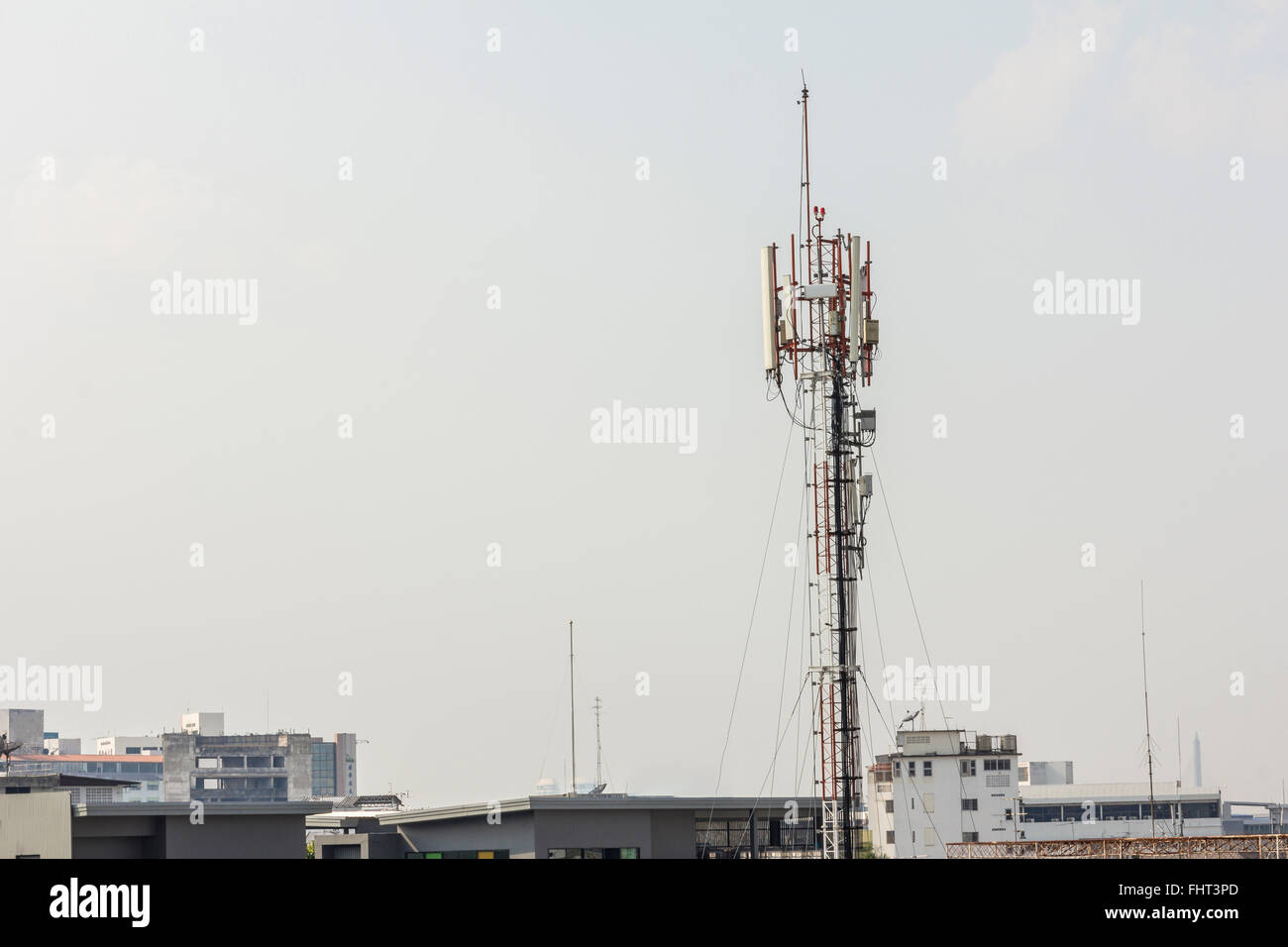 Torre di telecomunicazione con più antenne e trasmettitori di dati con la bella città in background e ampia montagna sono Foto Stock
