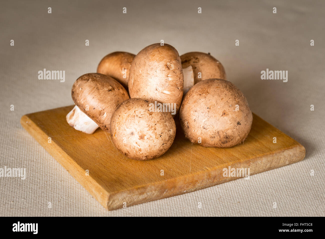 Fresca bruna funghi champignon, Agaricus bisporus, su una tavola di legno cutboard Foto Stock