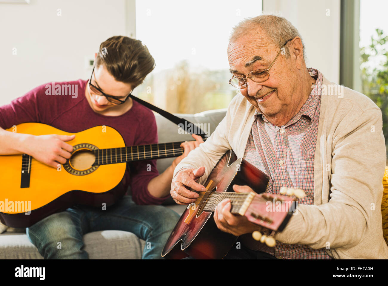Ritratto di uomo anziano a suonare la chitarra con il suo nipote Foto Stock