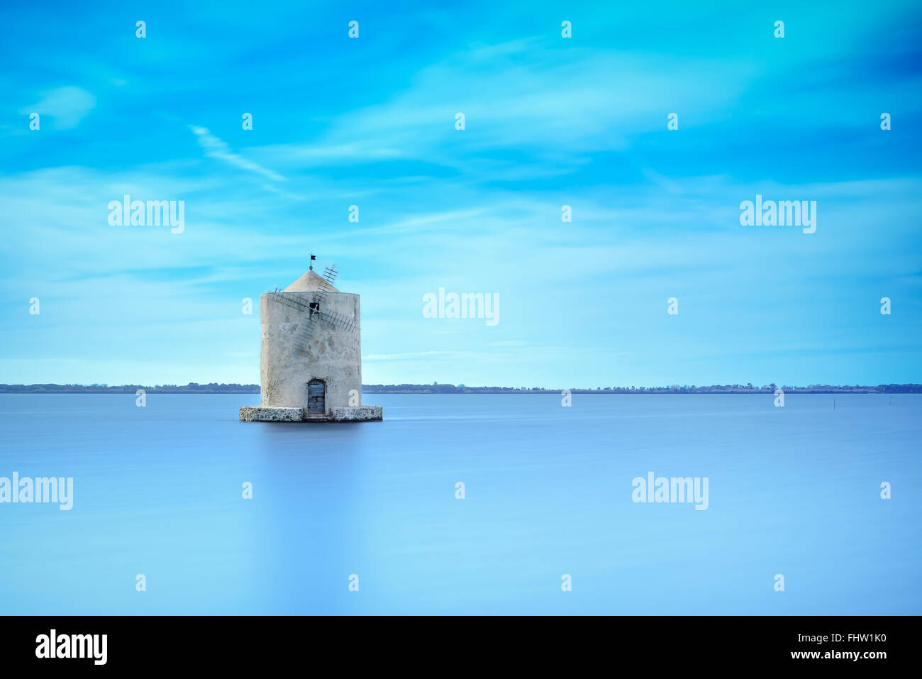 Vecchio mulino a vento spagnolo in una laguna blu. Molino Spagnolo landmark Orbetello, Monte Argentario, Toscana, Italia. Una lunga esposizione foto Foto Stock