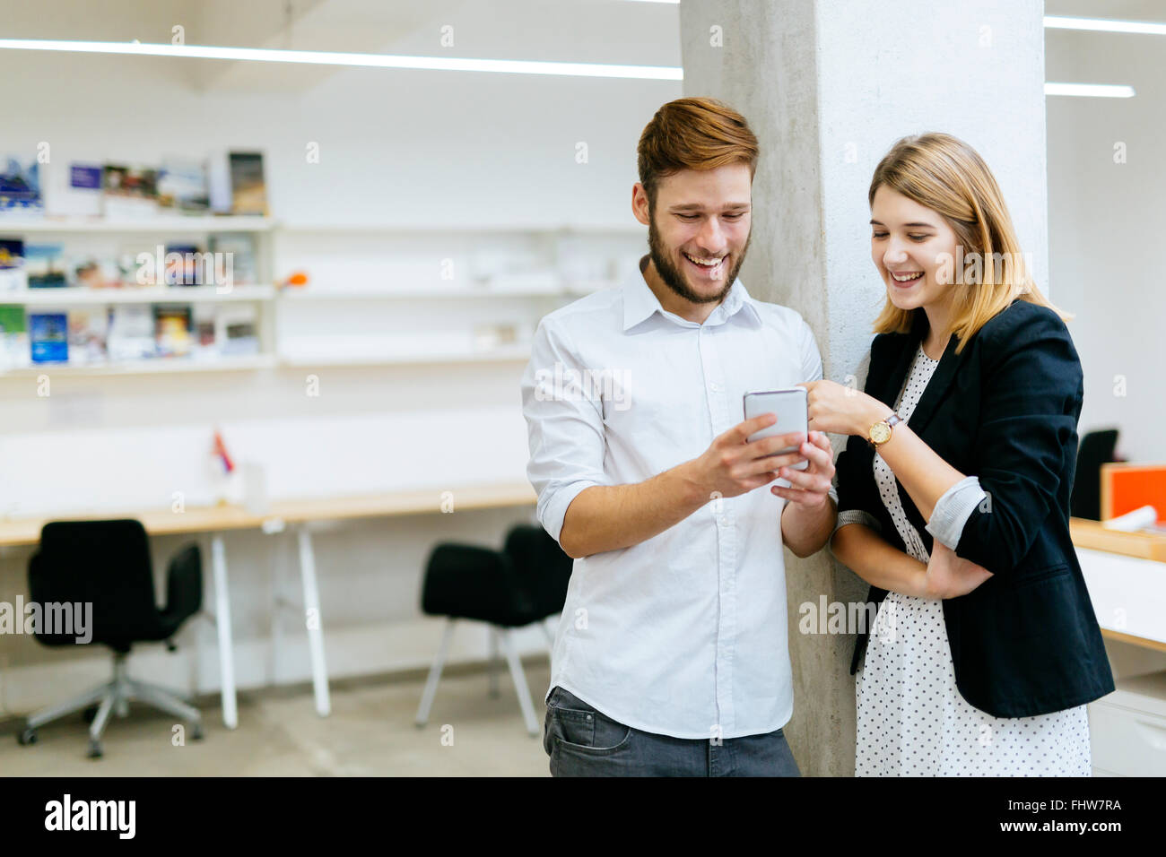 Imprenditore imprenditrice sorridere mentre guardando il telefono in ufficio Foto Stock