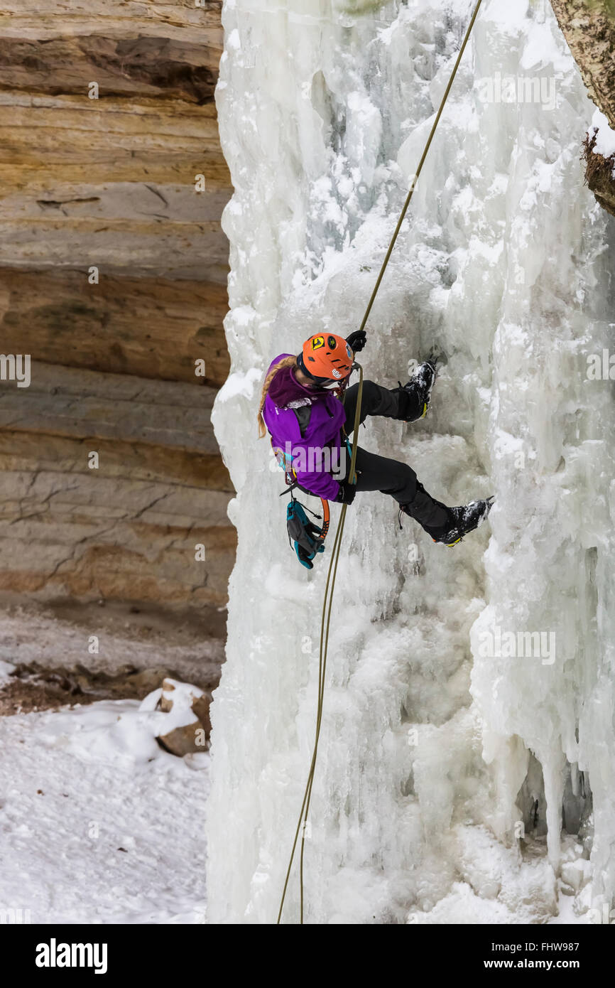 Donna ice climber rappelling giù una cascata ghiacciata in Pictured Rocks National Lakeshore, Penisola Superiore, Michigan, Stati Uniti d'America Foto Stock