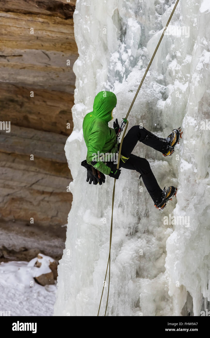 Ice Climber rappelling giù una cascata ghiacciata in Pictured Rocks National Lakeshore, Penisola Superiore, Michigan, Stati Uniti d'America Foto Stock