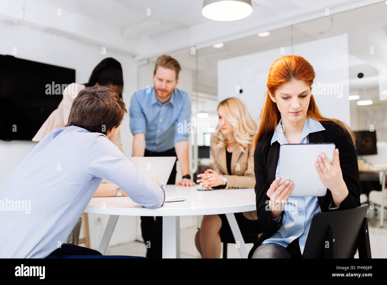 Colleghi di lavoro seduto alla scrivania con la tecnologia a portata di mano Foto Stock