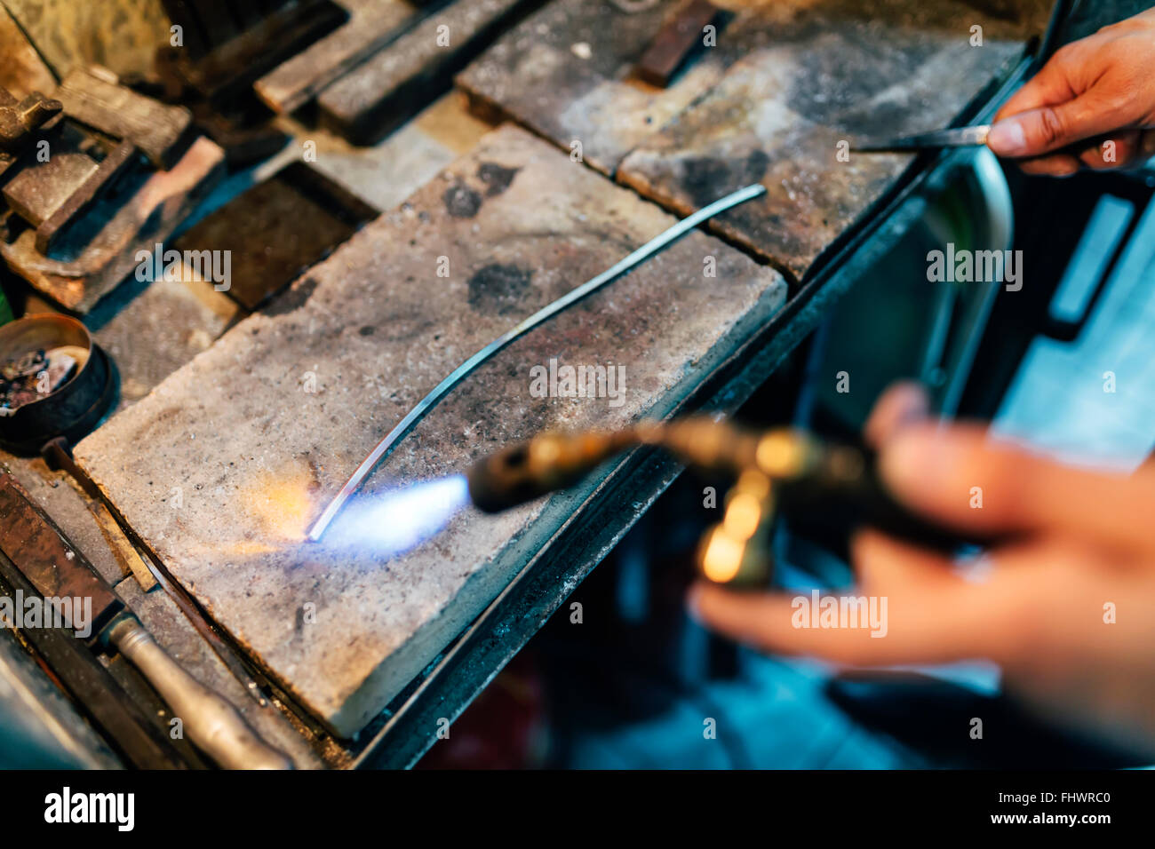 Il gioielliere di metallo di elaborazione mediante riscaldamento fino a una temperatura appropriata Foto Stock