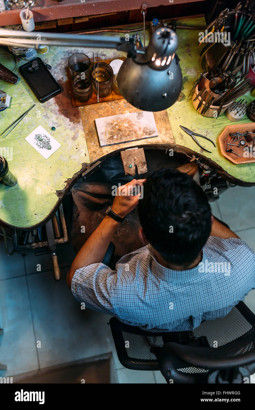 Il lavoro su un banco pieno di strumenti durante il delicato lavoro Foto Stock