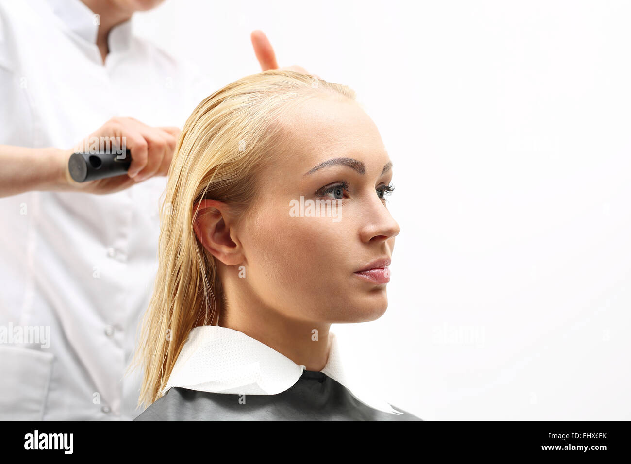 Di media lunghezza capelli, la donna presso il parrucchiere. La pettinatura dei capelli. La donna in sedia barbiere styling durante la chirurgia Foto Stock