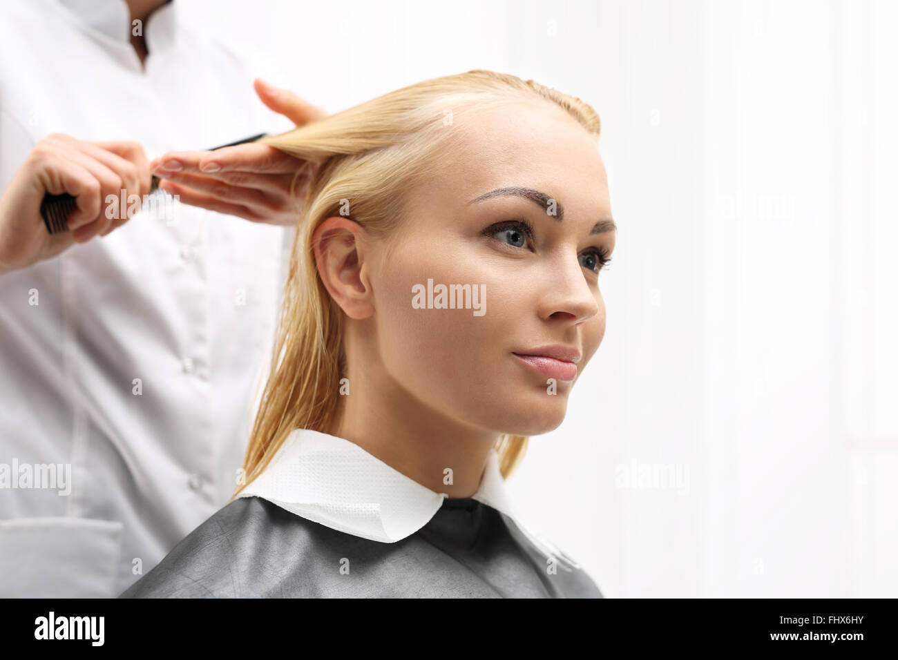 Di media lunghezza capelli, la donna presso il parrucchiere. La pettinatura dei capelli. La donna in sedia barbiere styling durante la chirurgia Foto Stock