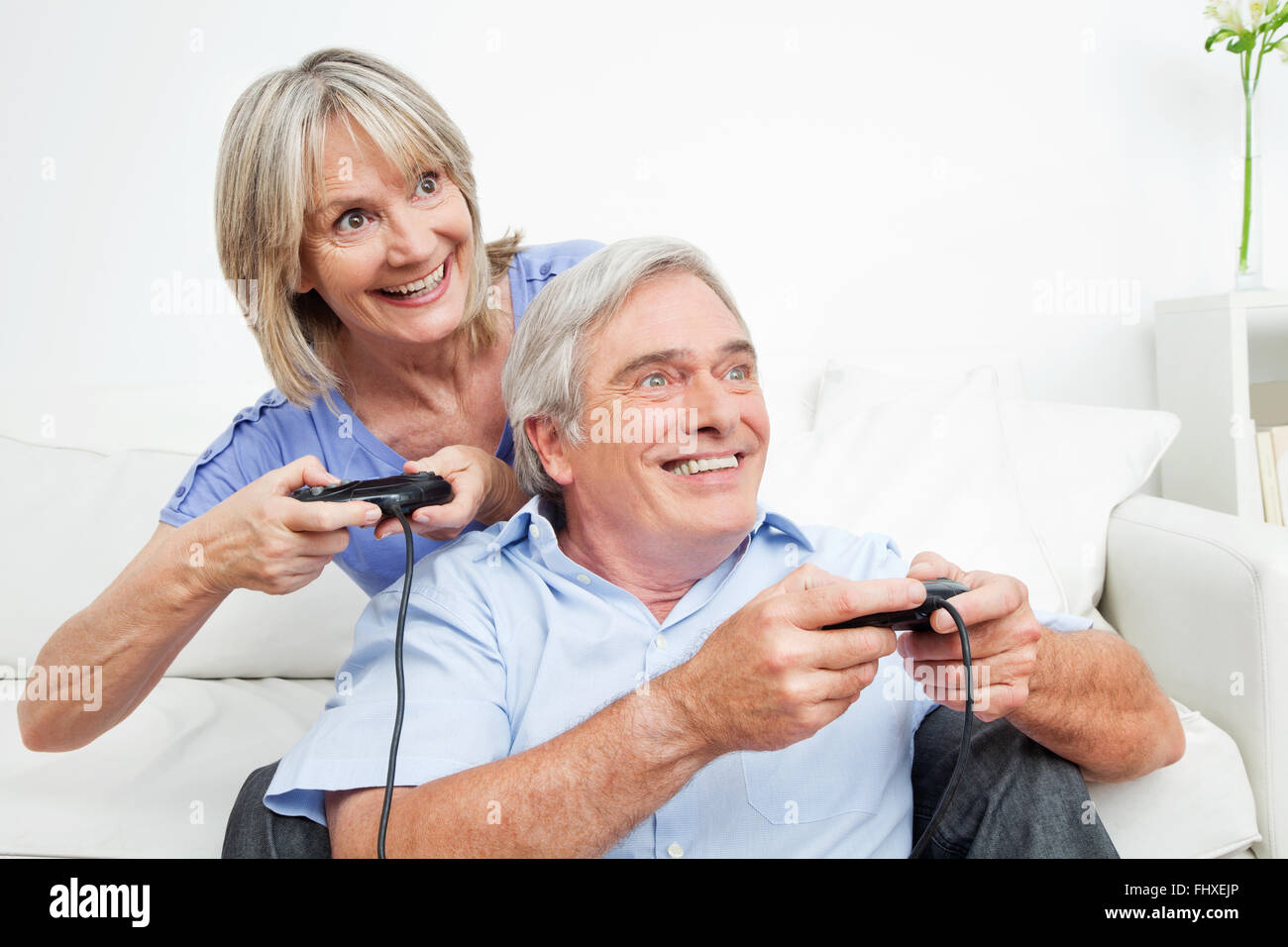 Felice coppia senior alla riproduzione di video giochi a casa con controller Foto Stock