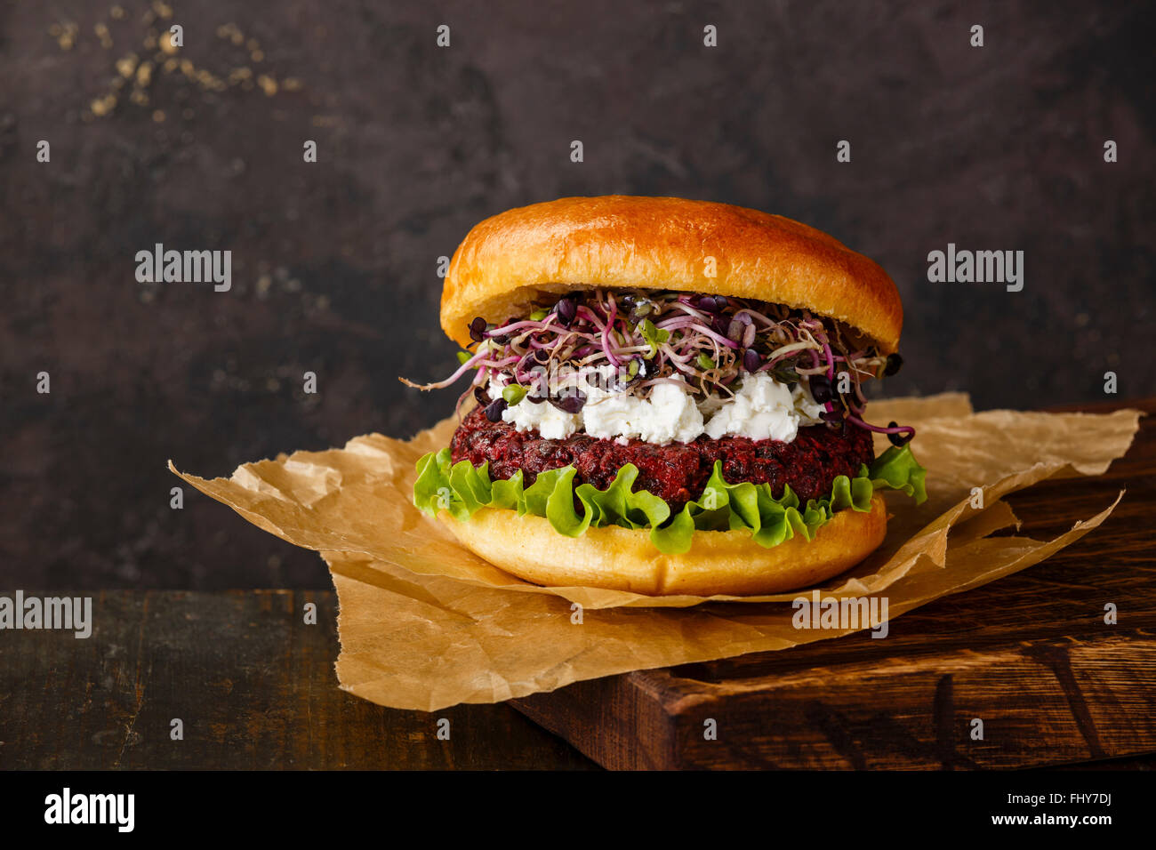 Burger di barbabietole con formaggio morbido e germogli di rafano su sfondo scuro Foto Stock