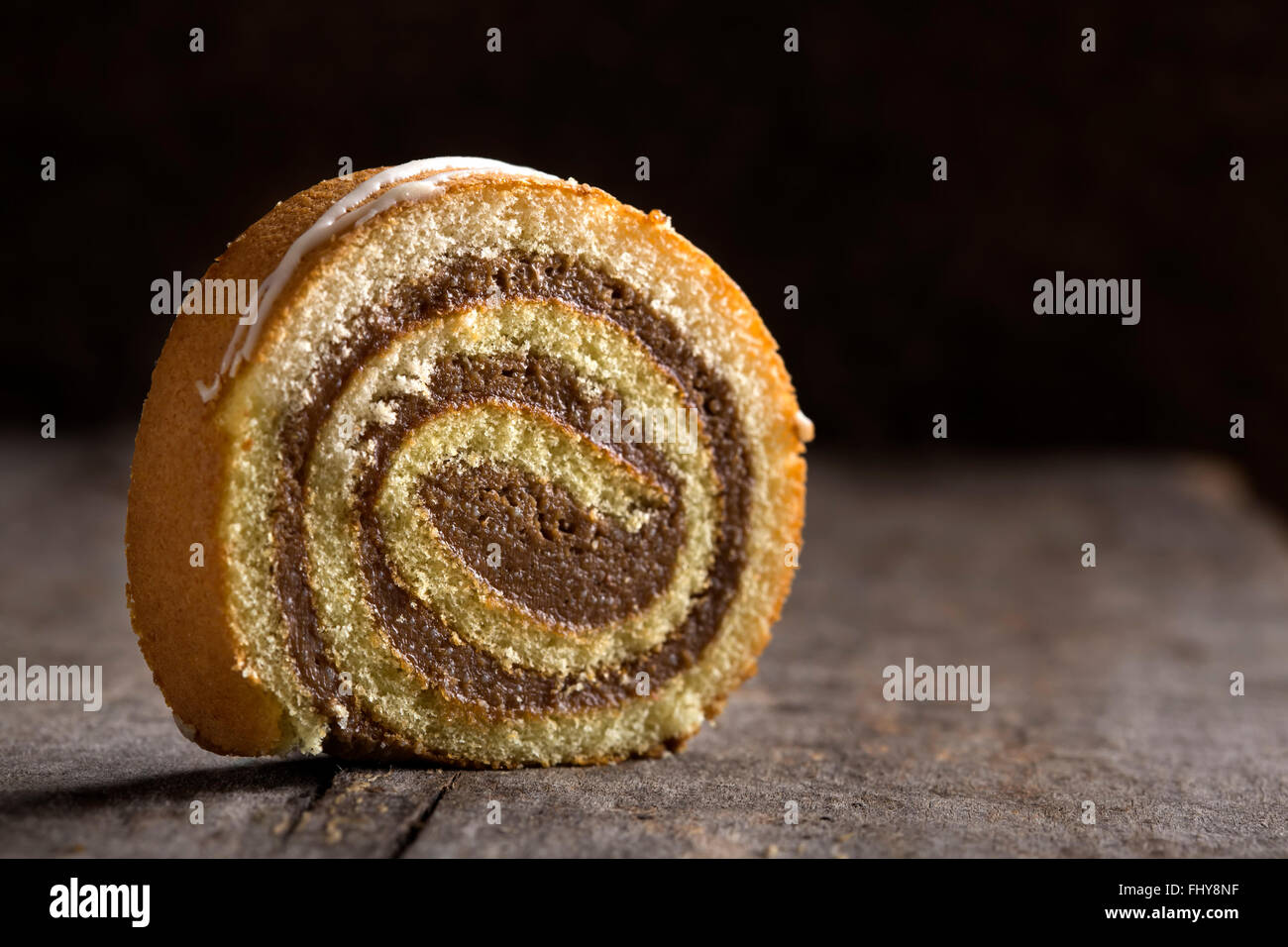 Rotolo di cioccolato torta con caramello e salsa alla vaniglia su sfondo di legno Foto Stock