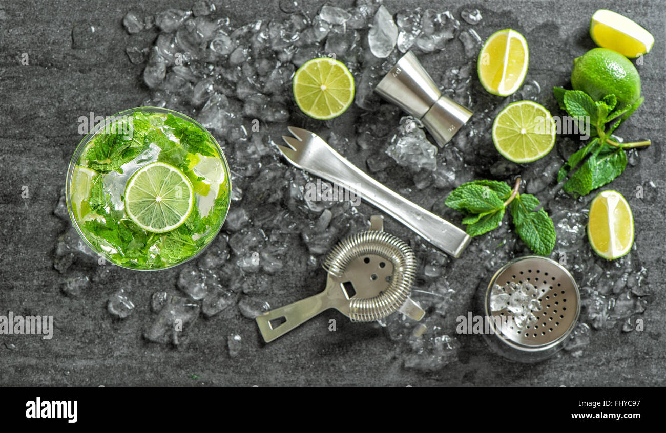 Bere rendendo gli accessori e gli ingredienti per un cocktail. Ghiaccio, lime e foglie di menta. Messa a fuoco selettiva su vetro Foto Stock