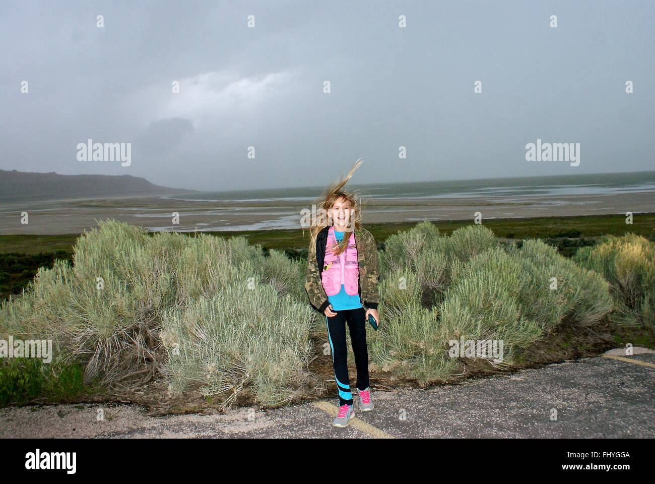 Giovane ragazza in piedi dalla spazzola con una tempesta di avvicinamento e i venti sono veramente soffiando i capelli in tutto. Foto Stock