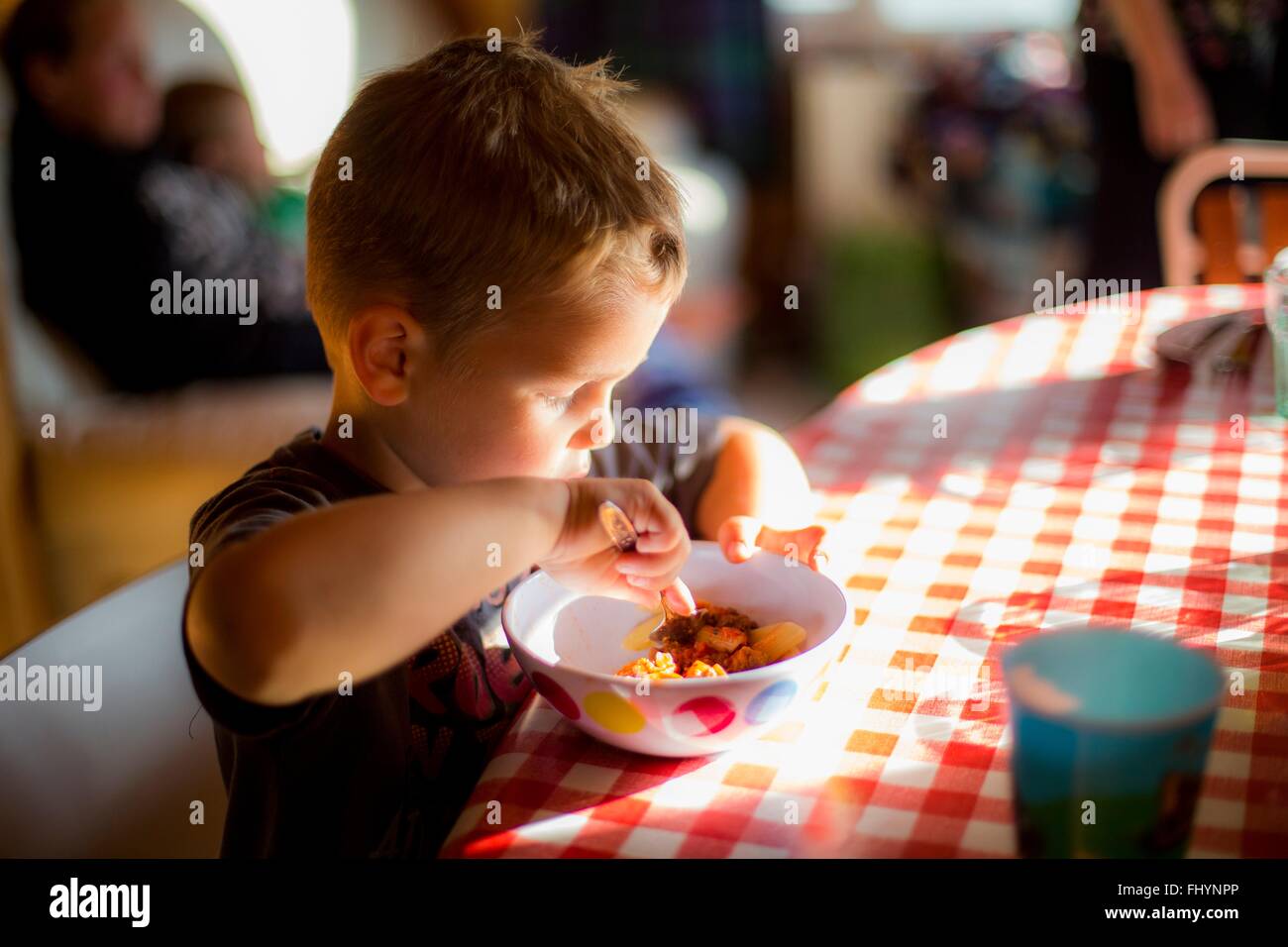 Modello rilasciato. Ragazzo seduto a tavola a mangiare un pasto. Foto Stock