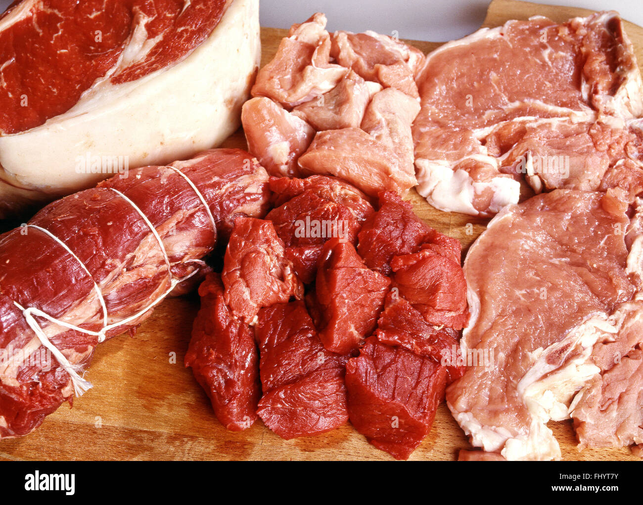 Assortimento di materie bovine e suine pezzi tagliati e preparato per la vendita o per la cottura su un tavolo di legno Foto Stock