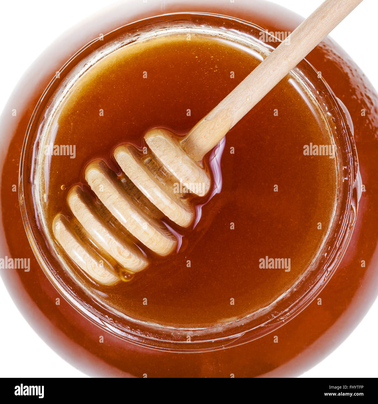Vista dall'alto di un cucchiaio di legno sul vasetto in vetro marrone con miele isolati su sfondo bianco Foto Stock
