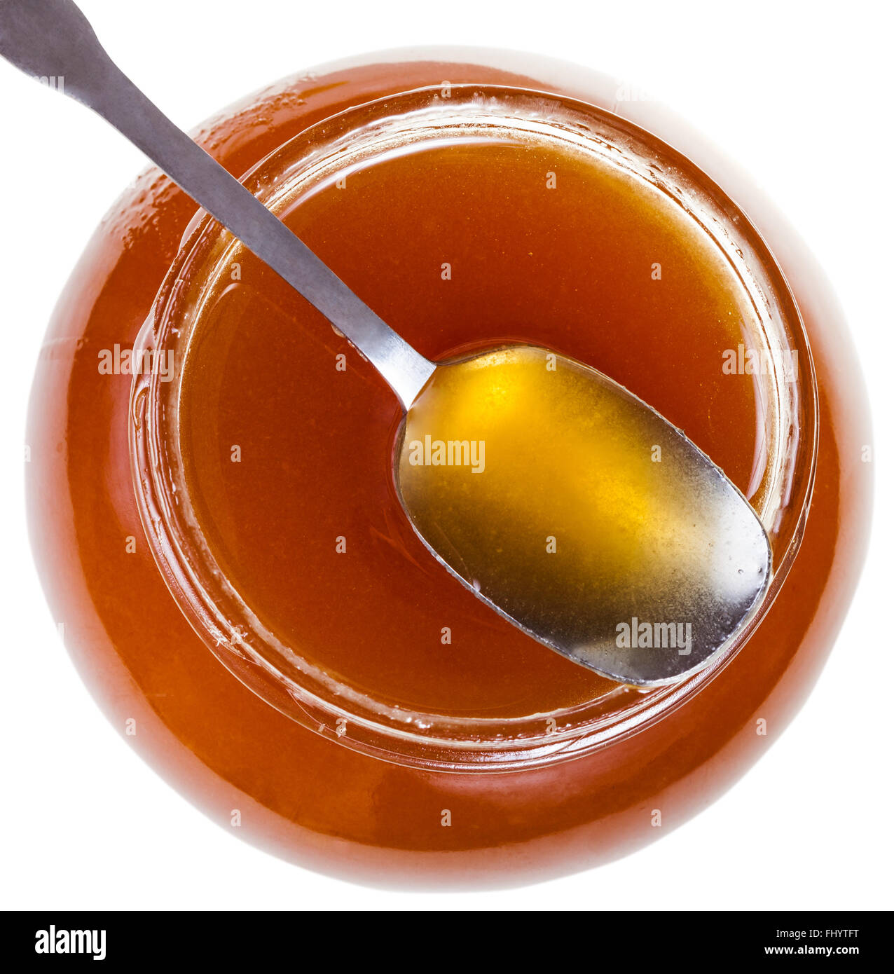 Al di sopra di vista del cucchiaio in acciaio sul vasetto in vetro marrone con miele isolati su sfondo bianco Foto Stock