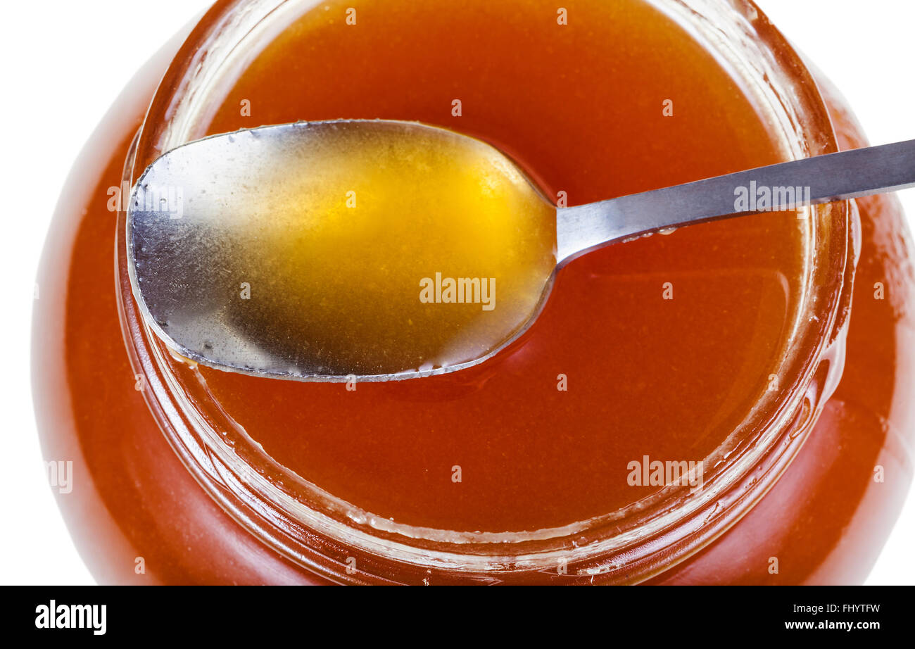 Vista superiore del cucchiaio di metallo sul vasetto in vetro marrone con miele isolati su sfondo bianco Foto Stock
