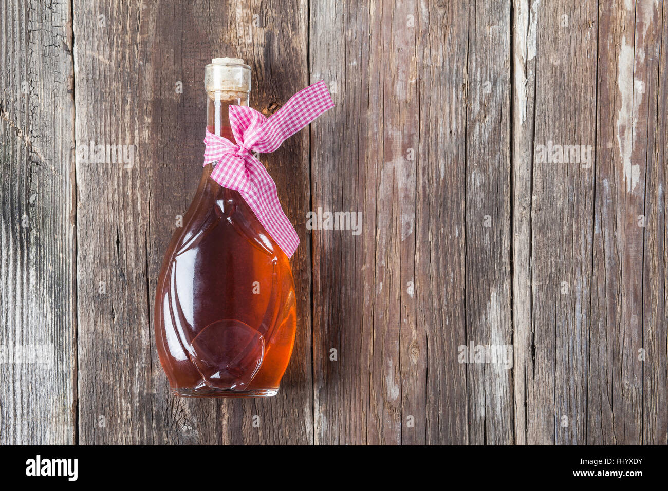 Trasparente piccola bottiglia piena di alcool sulla vecchia di tavole di legno Foto Stock