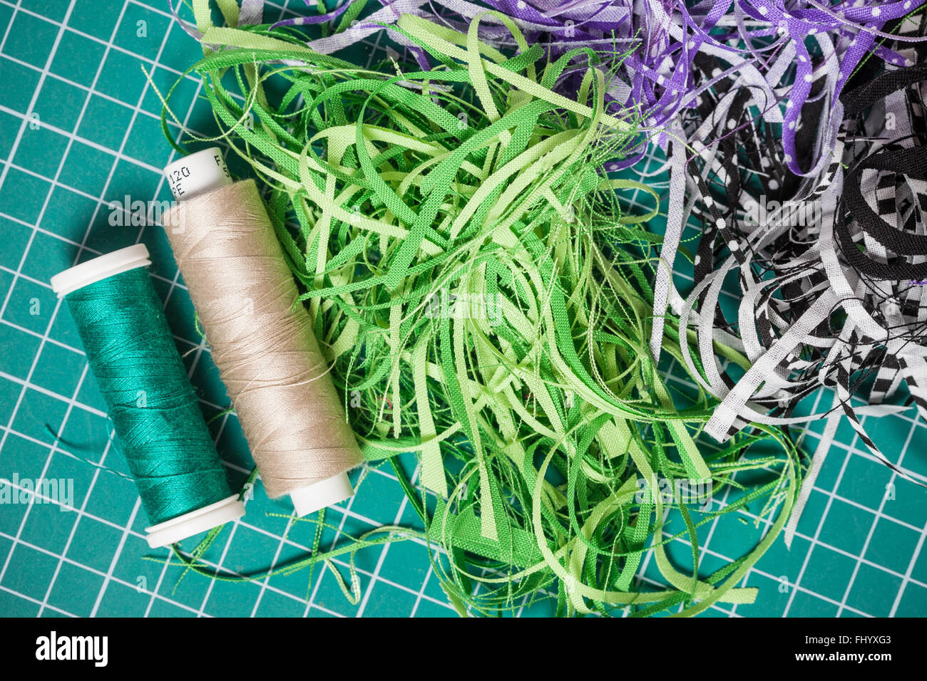 Fili di cucitura e residui tessili sul taglio verde a scacchi mat Foto Stock