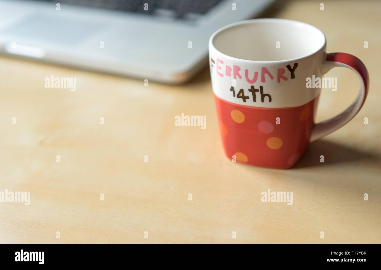 Svuotare Valentine's cup con tracciato di ritaglio e un laptop, copia dello spazio sul tavolo di legno Foto Stock
