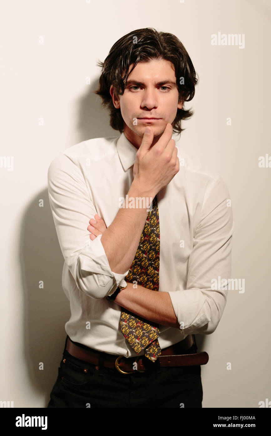 Giovane Uomo in camicia bianca e cravatta tenendo il suo pensiero mento. Foto Stock