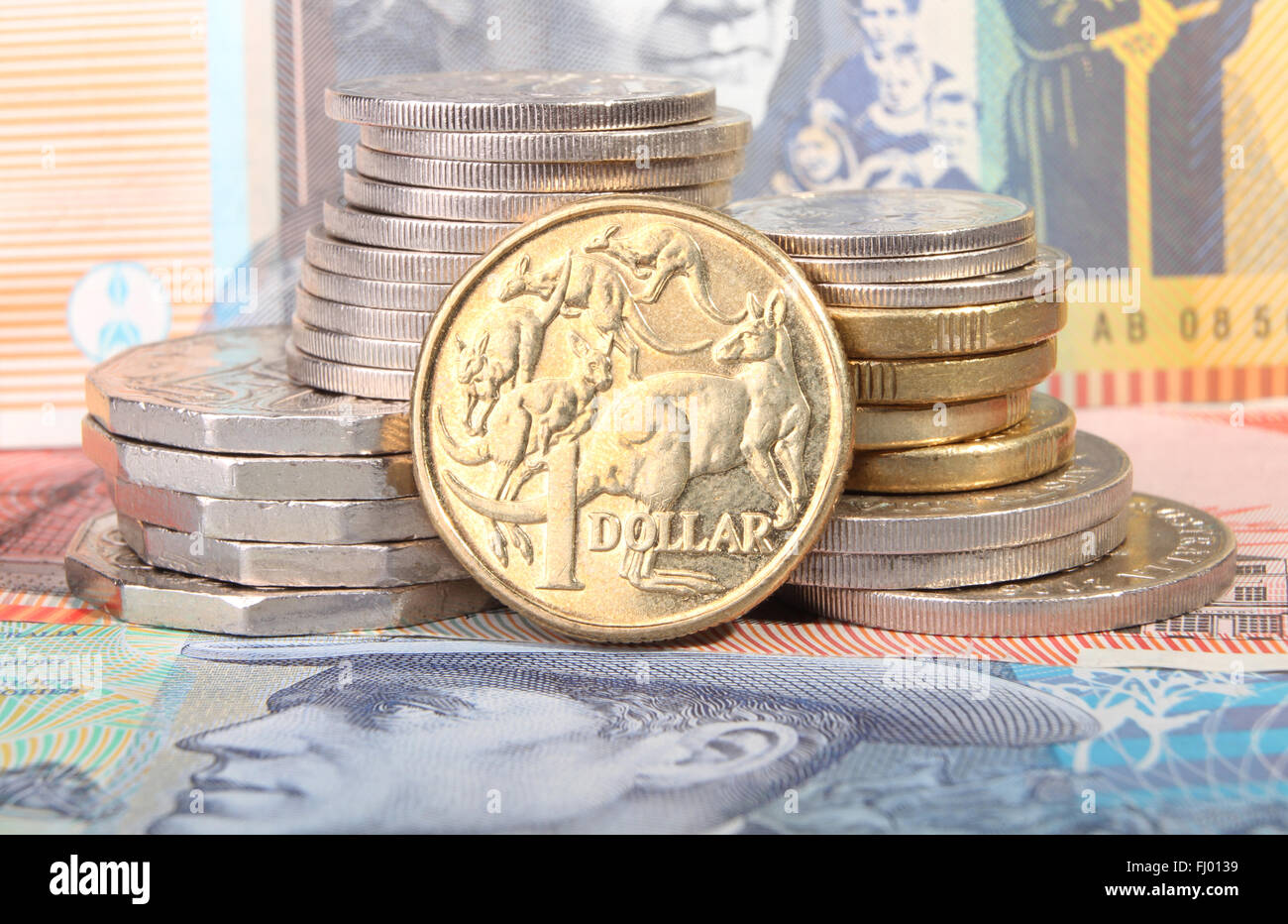 Un Australian Gold un dollaro moneta si siede accanto a una pila di monete sulla parte superiore della banca australiana note. Foto Stock