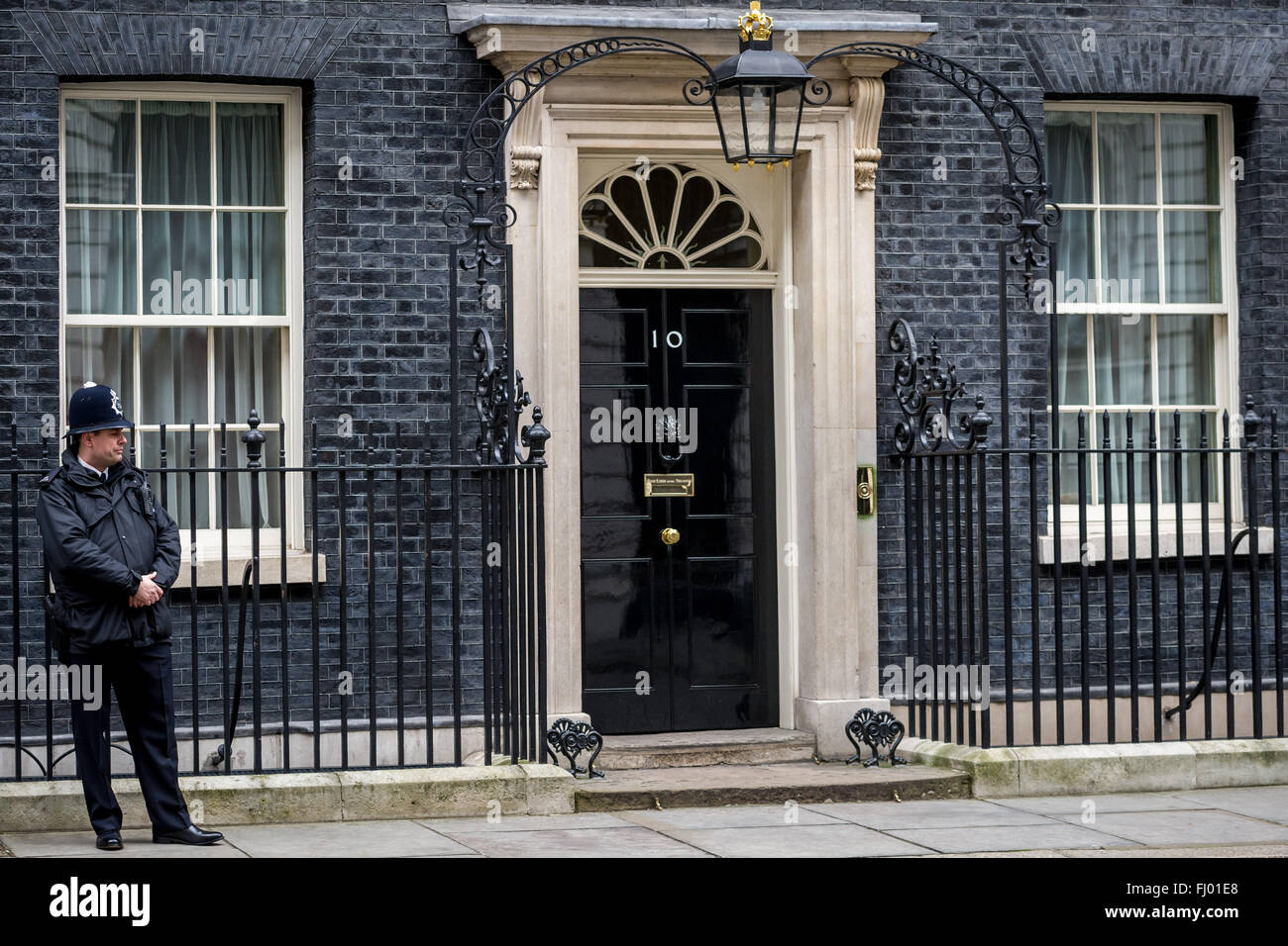 Un solitario funzionario di polizia sta alla porta anteriore al numero 10 di Downing Street. Il numero 10 è la residenza londinese della seduta del Primo ministro britannico e il quartier generale del ramo esecutivo del governo britannico. Dotato di: numero 10 di Downing Street, funzionario di polizia, vista in cui: Londra, Regno Unito quando: 27 Gen 2016 Foto Stock