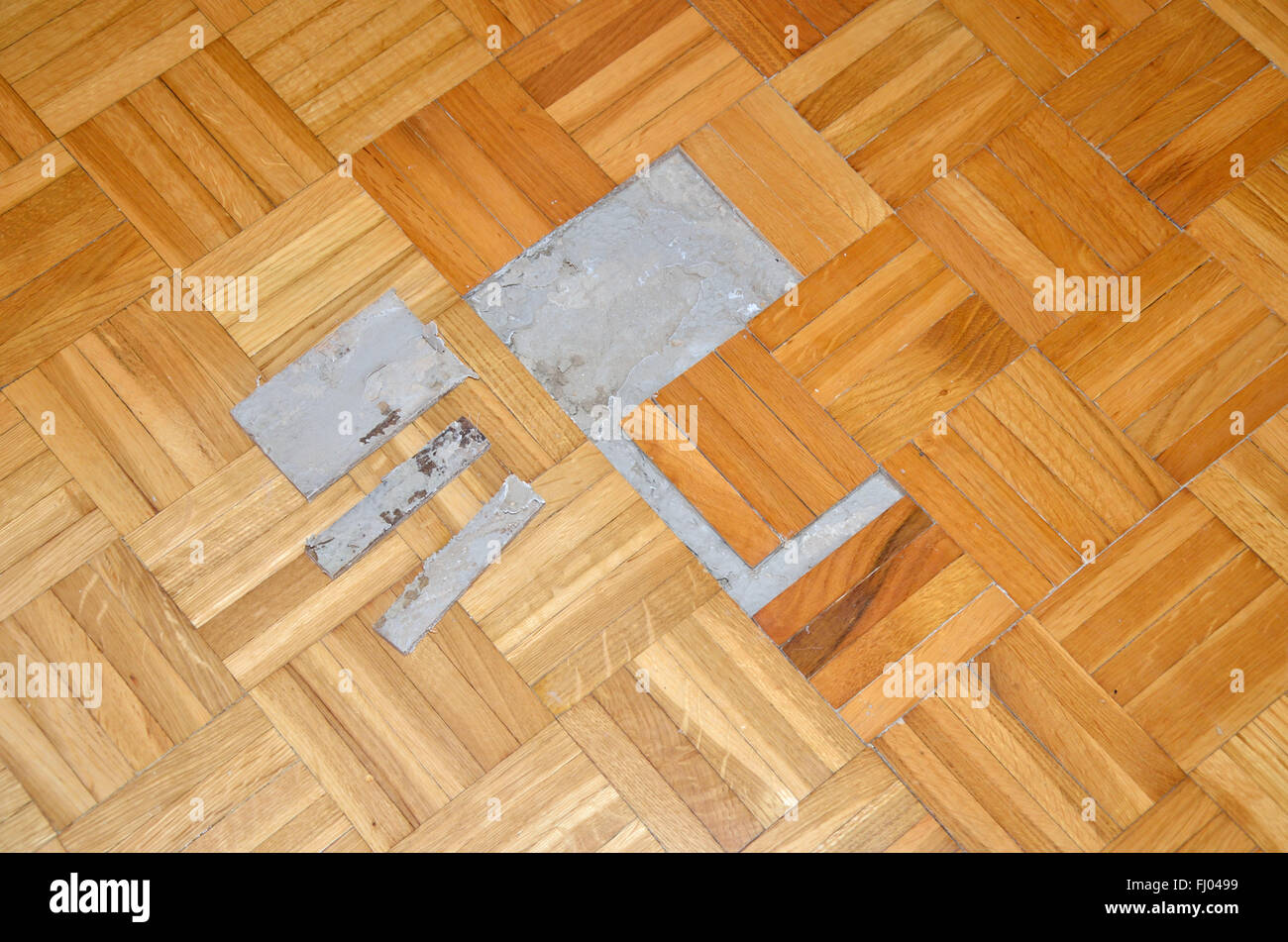 Danneggiato Il parquet in legno con parti rimosse e parquet visibile il vecchio adesivo incolla Foto Stock