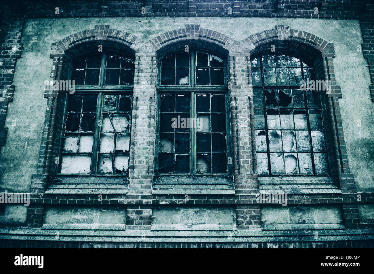 Il vecchio edificio abbandonato con rotture di finestre ad arco Foto Stock