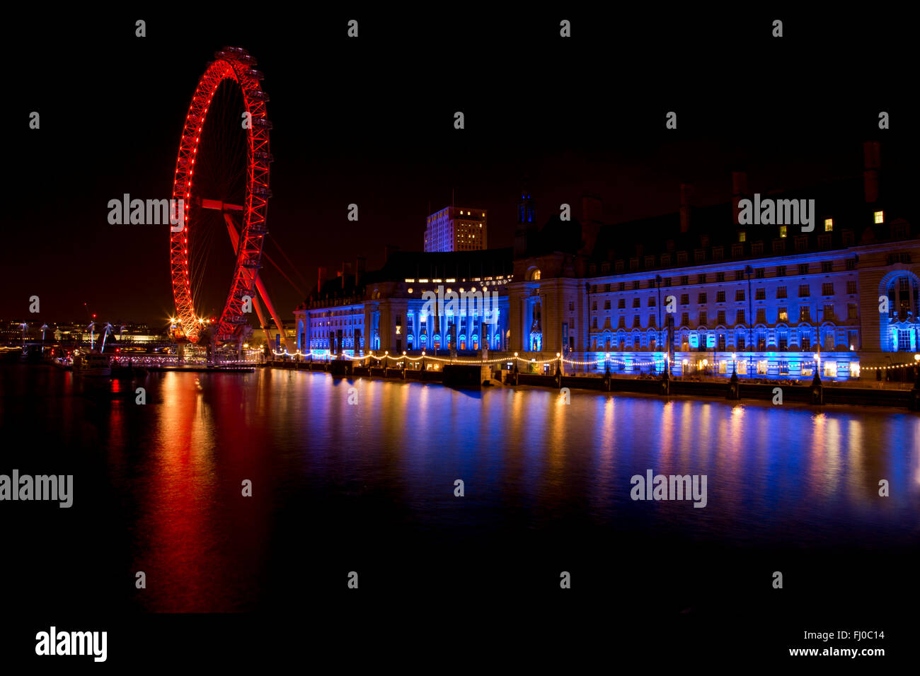 London Eye e County Hall con riflessi di luce colorata sul fiume Tamigi Foto Stock