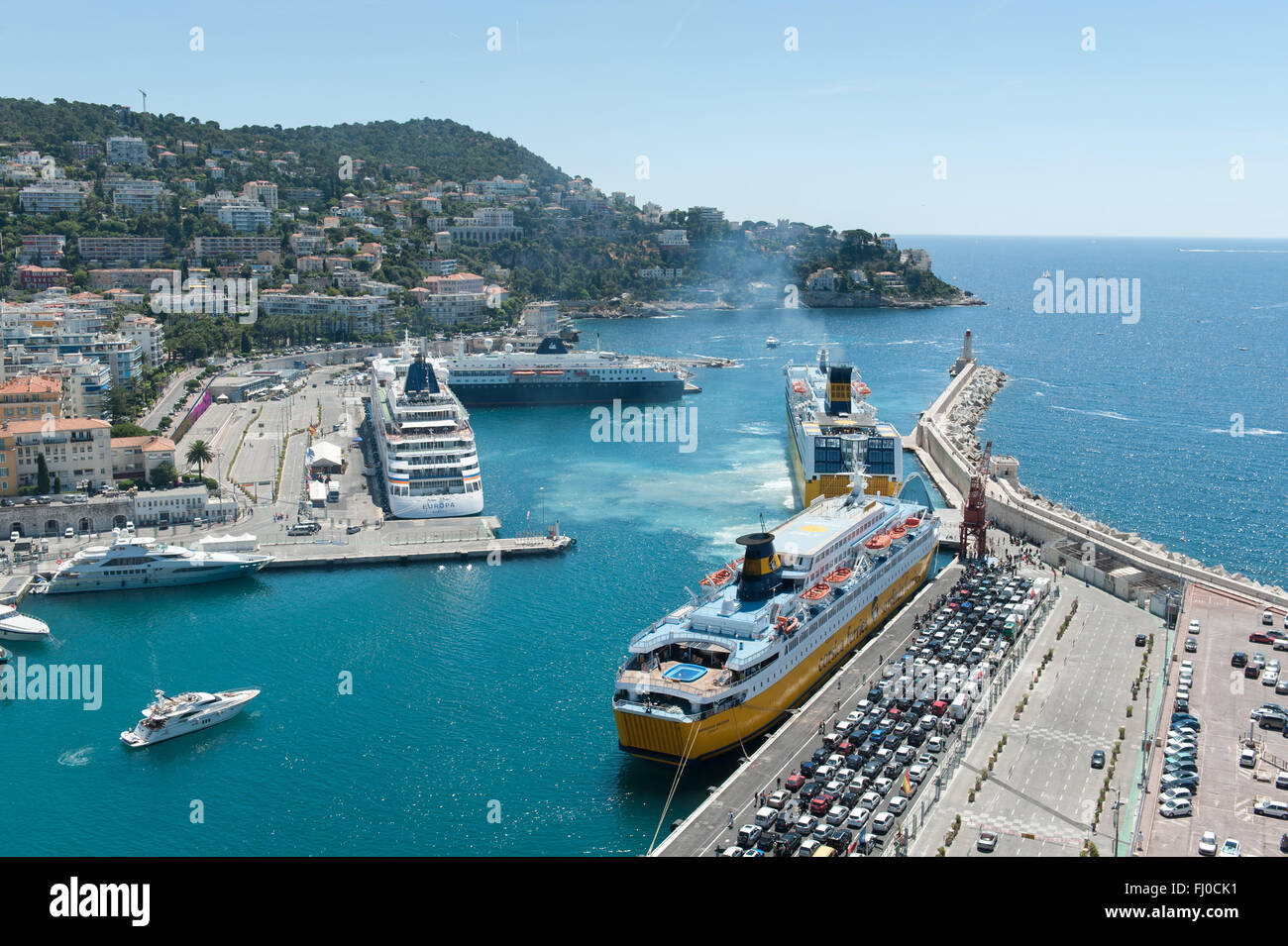 Una Corsica traghetto per auto con veicoli in coda al bord, e di una nave da crociera, Ormeggiato accanto alla banchina del porto di Nizza, Francia Foto Stock