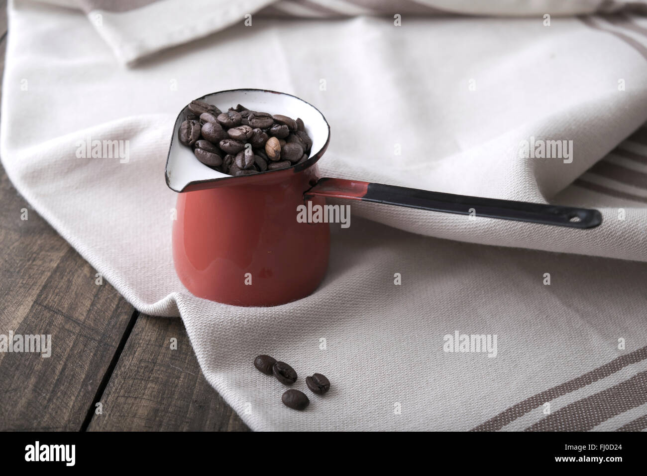 I chicchi di caffè in una tazza di smalto sullo sfondo di legno Foto Stock