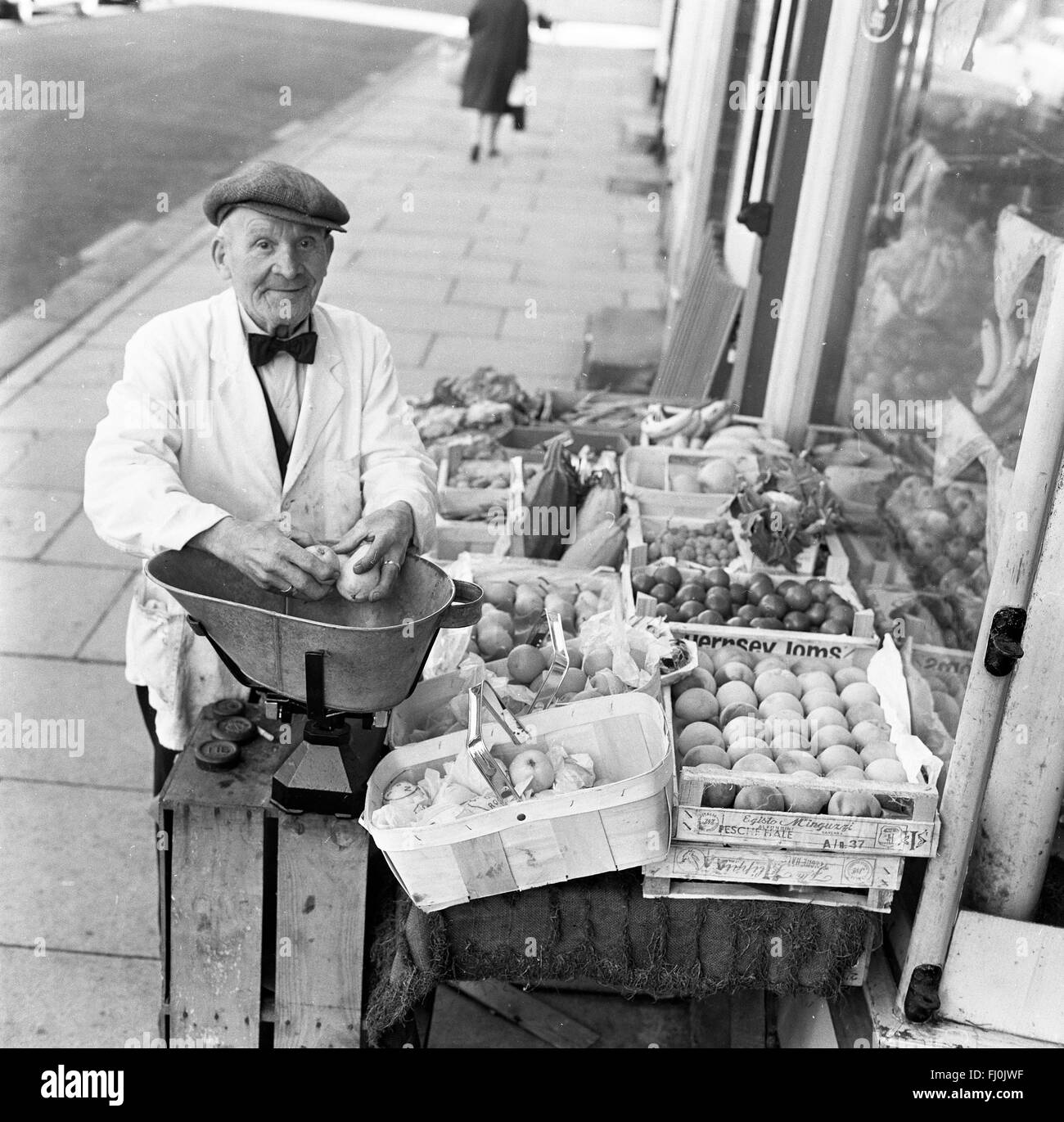 La frutta e la verdura uomo negozio di vendita di produrre a indipendenti di high street shop negli anni sessanta Foto Stock