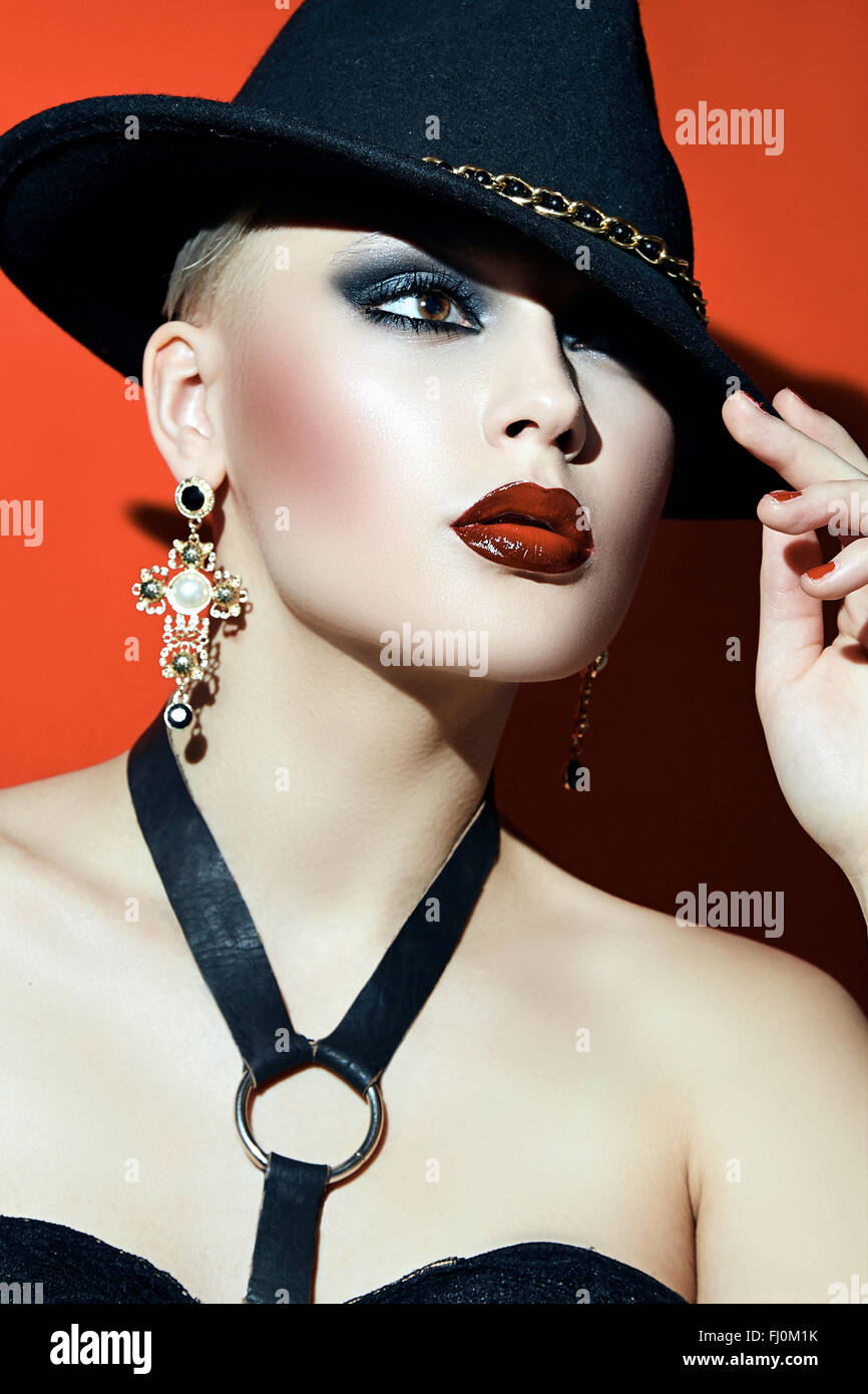 Rock Girl in un cappello nero con labbra rosse e occhi scuri in un corsetto. Foto Stock