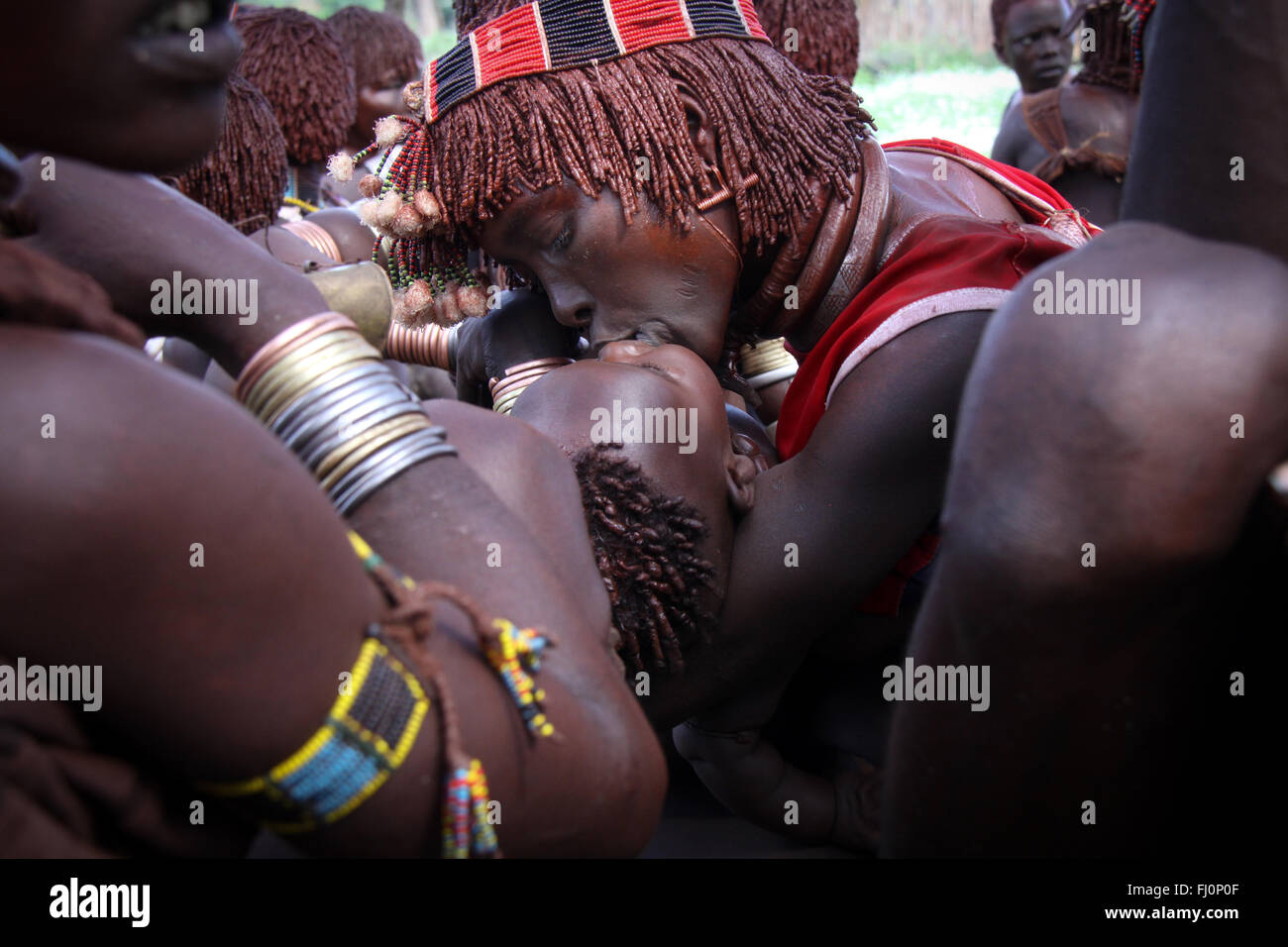 Una madre bacia il bambino durante una cerimonia di premiazione che si terrà da hamer tribù nella valle dell'Omo, Etiopia, vicino a Turmi Foto Stock