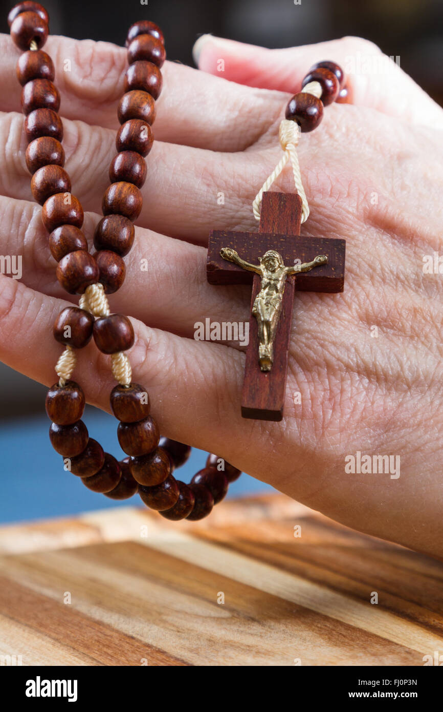 In prossimità di una donna di mani tenendo il rosario focalizzata sulla croce Foto Stock