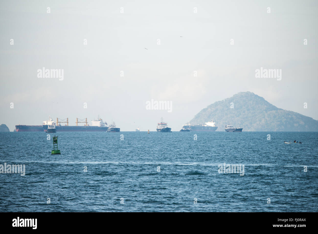 Canale di Panama navi container Panama Bay Panama // CANALE DI PANAMA, Panama — navi container e passeggeri ancorano nella Baia di Panama in attesa del transito previsto attraverso il Canale di Panama da sud a nord. La via d'acqua strategica, completata nel 1914, collega l'Oceano Atlantico e l'Oceano Pacifico, eliminando la necessità per le navi di navigare in Sud America. Il canale funziona utilizzando un sistema di chiuse che sollevano le navi verso il lago Gatun, 85 piedi sopra il livello del mare, prima di abbassarle nuovamente al livello del mare sul lato opposto. I tempi di transito variano in genere da 8 a 10 ore, con le navi che spesso aspettano giorni Foto Stock