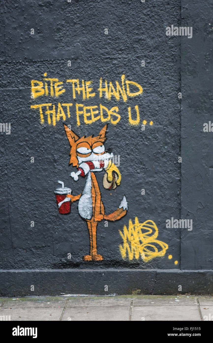 Mordere la mano che ti nutre i graffiti sulla facciata di un edificio di Stokes Croft, Bristol Foto Stock