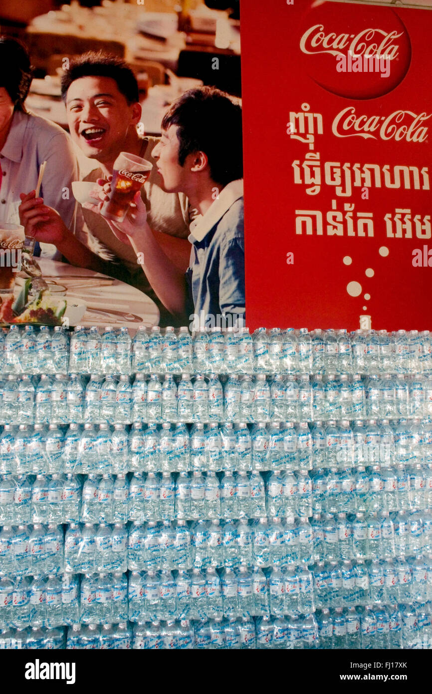Le bottiglie di plastica sono impilati sotto un grande Coca Cola pubblicità segno in un ristorante Skun, Kampong Cham provincia, in Cambogia. Foto Stock