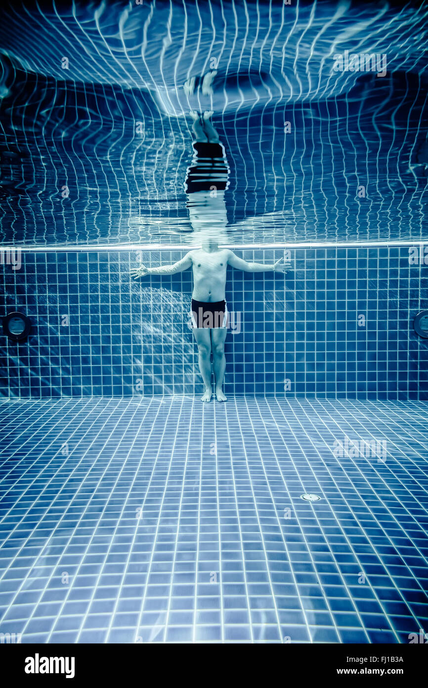 Uomo in piedi sotto acqua in una piscina Foto Stock